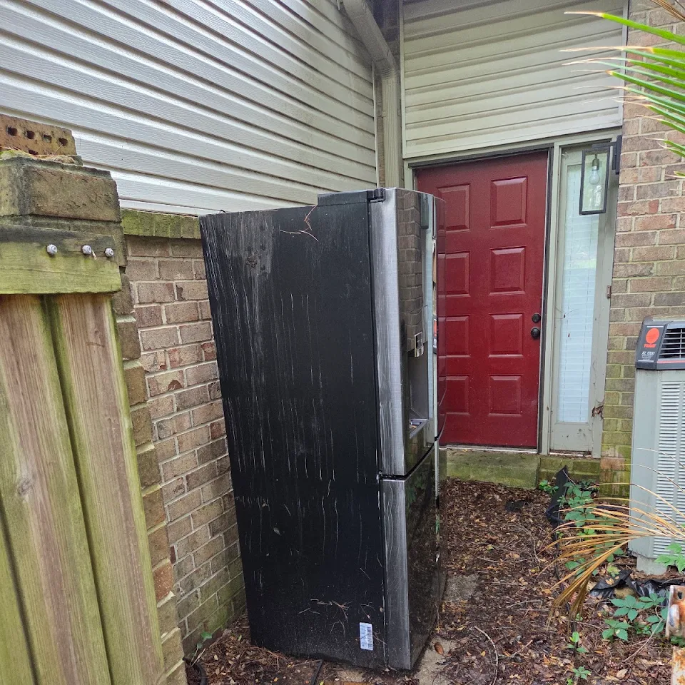 Old refrigerator set out beside a house for removal